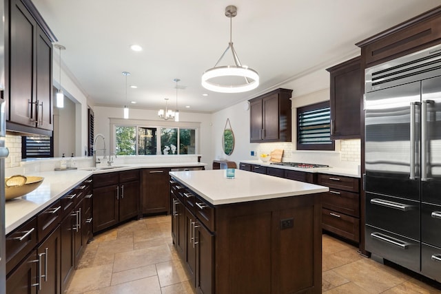 kitchen featuring appliances with stainless steel finishes, sink, decorative light fixtures, backsplash, and a kitchen island