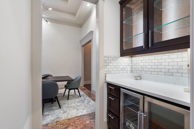 bar featuring dark brown cabinets, a raised ceiling, crown molding, and tasteful backsplash