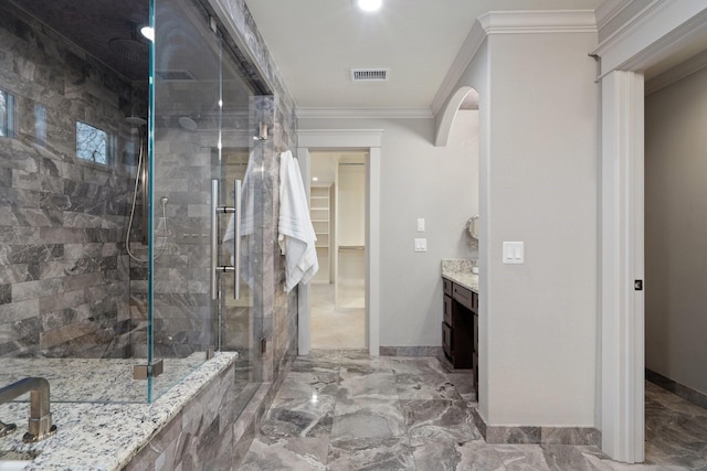 bathroom featuring a shower with shower door, vanity, and crown molding