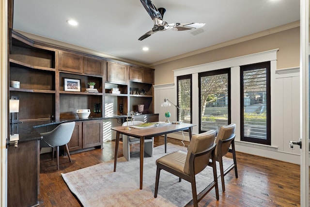 home office with ceiling fan, built in desk, ornamental molding, and dark hardwood / wood-style floors