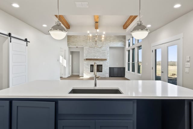 kitchen with sink, pendant lighting, beamed ceiling, and a barn door