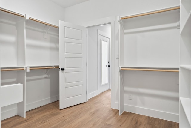 walk in closet with light hardwood / wood-style flooring