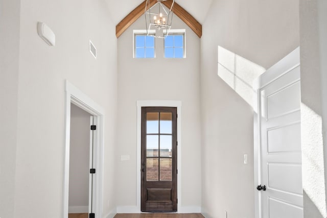 entrance foyer with a notable chandelier, high vaulted ceiling, beam ceiling, and hardwood / wood-style floors