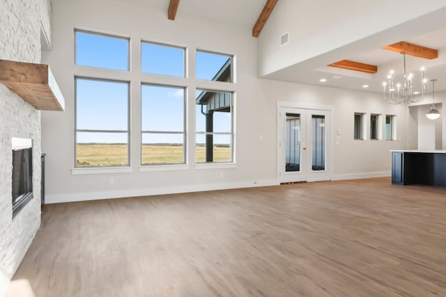 unfurnished living room with hardwood / wood-style flooring, a stone fireplace, a healthy amount of sunlight, and beam ceiling