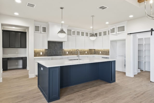 kitchen featuring a spacious island, white cabinetry, light hardwood / wood-style floors, sink, and a barn door