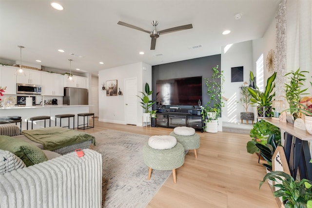 living room with light hardwood / wood-style floors and ceiling fan