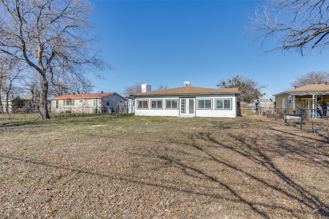 rear view of house featuring a yard, fence, and a chimney