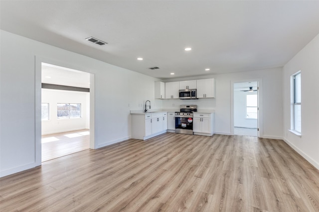 unfurnished living room with sink, light hardwood / wood-style floors, and ceiling fan