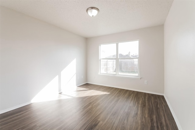 empty room featuring a textured ceiling and dark hardwood / wood-style flooring