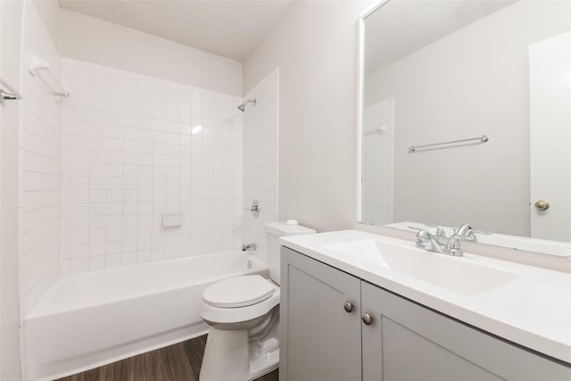 full bathroom featuring toilet, a textured ceiling, wood-type flooring, vanity, and tiled shower / bath