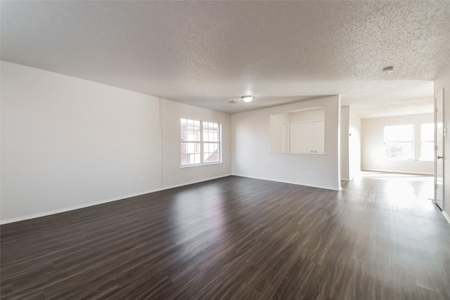 spare room featuring a textured ceiling and dark hardwood / wood-style floors