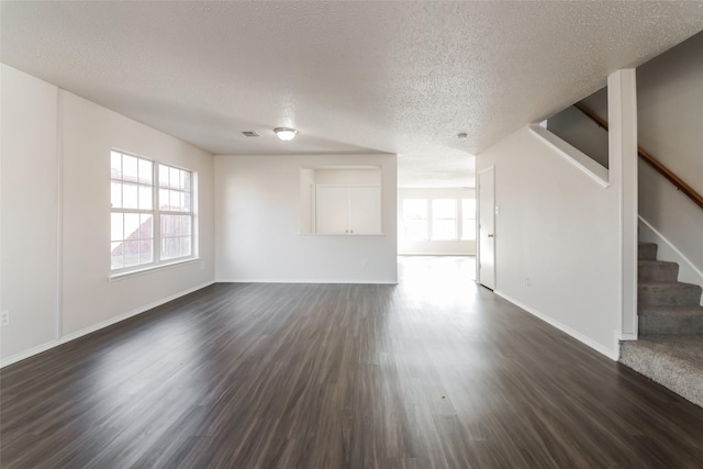 unfurnished living room with dark hardwood / wood-style flooring, a wealth of natural light, and a textured ceiling