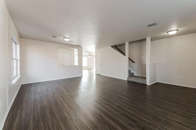 unfurnished living room featuring dark wood-type flooring, a textured ceiling, and ceiling fan