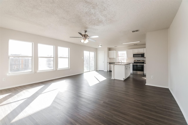 unfurnished living room with ceiling fan, sink, a textured ceiling, and dark hardwood / wood-style floors