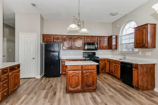 kitchen featuring black appliances, a kitchen island, light hardwood / wood-style floors, sink, and hanging light fixtures