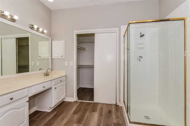 bathroom with wood-type flooring, walk in shower, and vanity