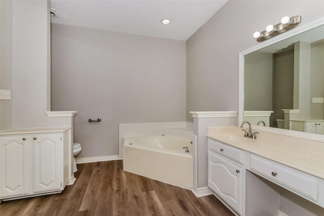 bathroom featuring vanity, toilet, hardwood / wood-style floors, and a washtub