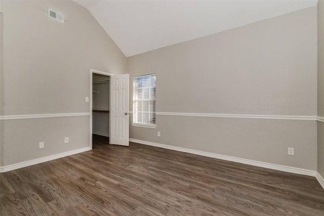 unfurnished bedroom with a closet, dark hardwood / wood-style floors, a spacious closet, and lofted ceiling