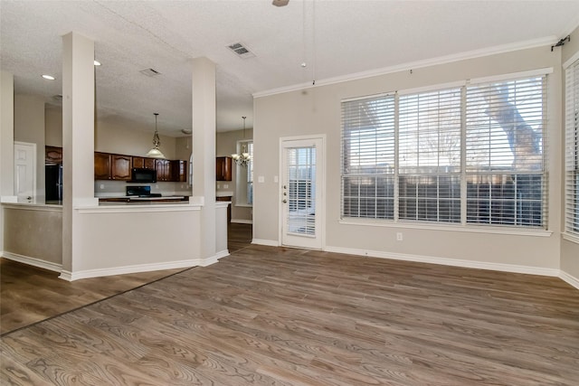 unfurnished living room with a textured ceiling, dark hardwood / wood-style flooring, ornamental molding, and an inviting chandelier