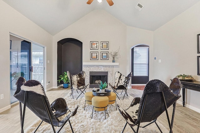 living area with vaulted ceiling, a fireplace, visible vents, and light wood-style floors