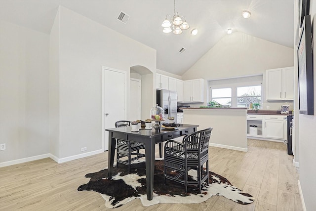 dining area with light hardwood / wood-style flooring, high vaulted ceiling, and a chandelier