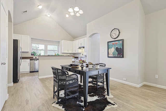 dining room featuring light wood-style flooring, visible vents, a chandelier, and arched walkways