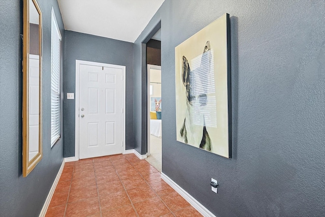 corridor with baseboards and tile patterned floors