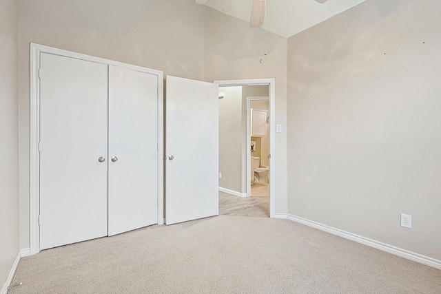 unfurnished bedroom featuring a ceiling fan, baseboards, vaulted ceiling, a closet, and carpet