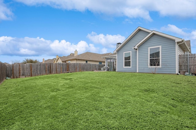 back of property with a fenced backyard and a lawn