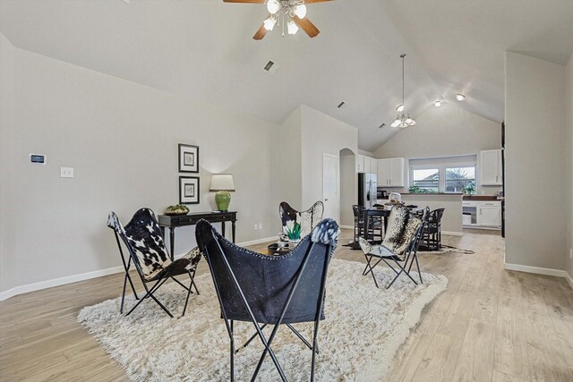 living room with high vaulted ceiling, arched walkways, light wood-style flooring, and baseboards