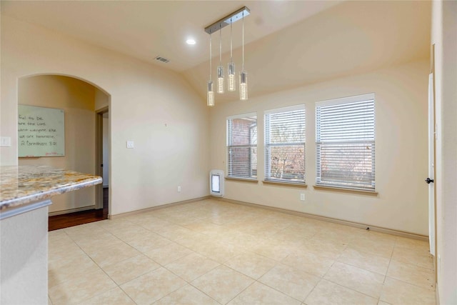 unfurnished dining area with light tile patterned floors and vaulted ceiling