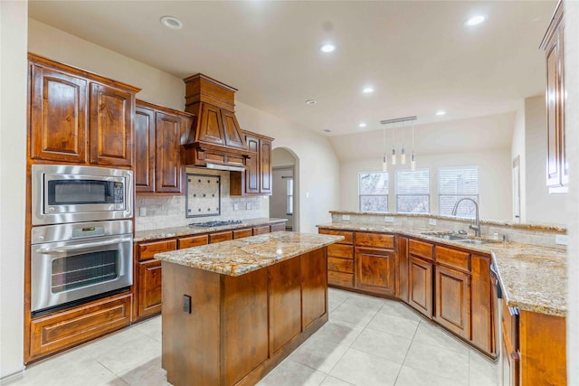 kitchen featuring a center island, light stone countertops, sink, pendant lighting, and stainless steel appliances