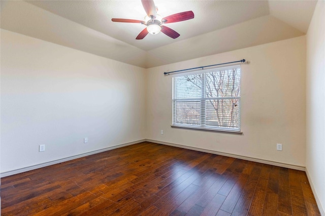 empty room with ceiling fan, dark wood-type flooring, a raised ceiling, and vaulted ceiling