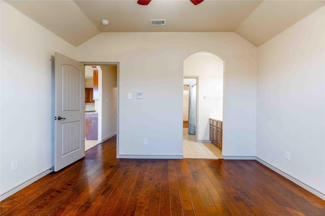 unfurnished bedroom featuring ceiling fan, hardwood / wood-style floors, ensuite bathroom, and vaulted ceiling