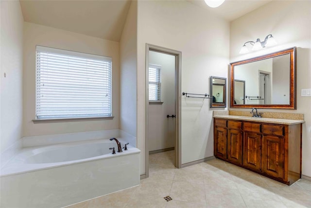 bathroom with a healthy amount of sunlight, a tub to relax in, tile patterned floors, and vanity