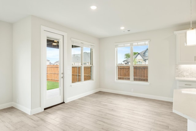 unfurnished dining area with recessed lighting, baseboards, light wood-type flooring, and visible vents