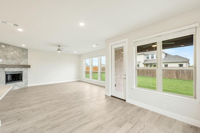 unfurnished living room with visible vents, wood finished floors, baseboards, a ceiling fan, and a premium fireplace