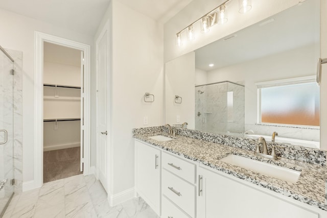 full bathroom with a walk in closet, a marble finish shower, and a sink