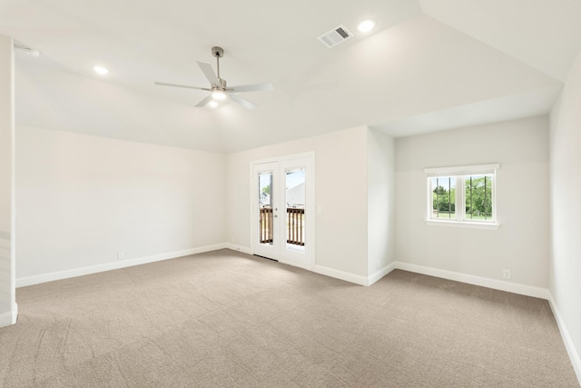 carpeted spare room with vaulted ceiling, a wealth of natural light, a ceiling fan, and visible vents