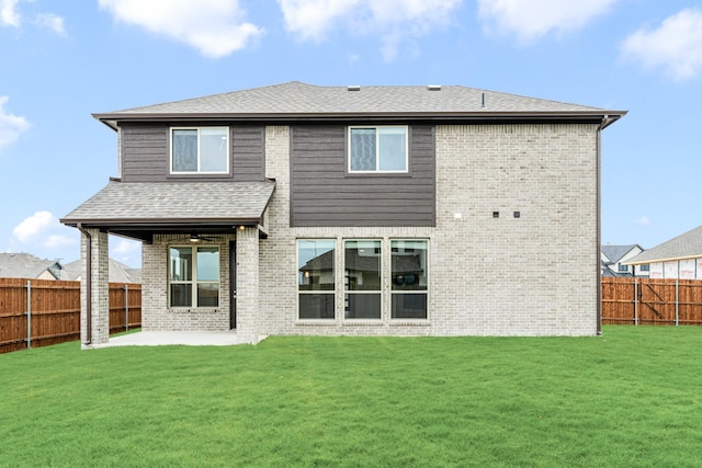 rear view of property featuring a yard, brick siding, a fenced backyard, and a patio area