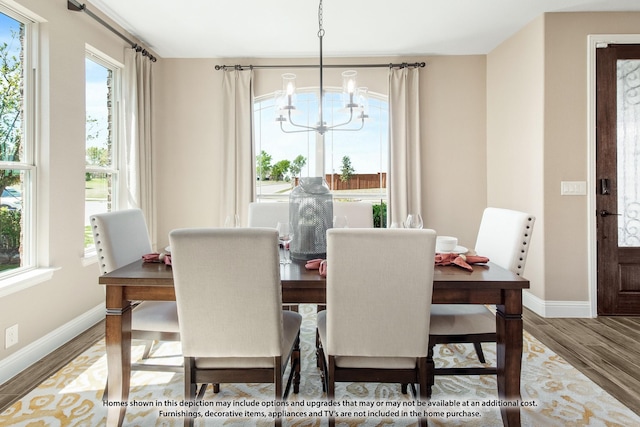 dining area with a healthy amount of sunlight, hardwood / wood-style floors, and a chandelier