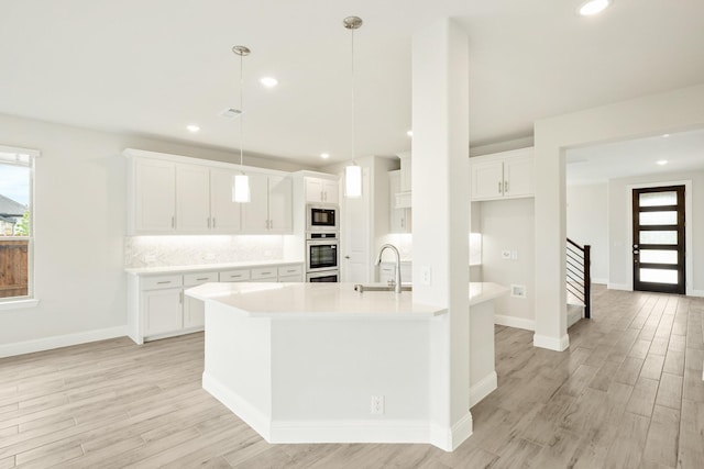 kitchen with light wood-style floors, a sink, black microwave, and light countertops