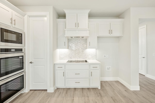 kitchen with baseboards, tasteful backsplash, black appliances, and light wood-style flooring