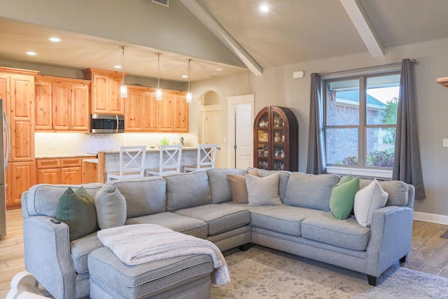 living room with lofted ceiling with beams and light wood-type flooring