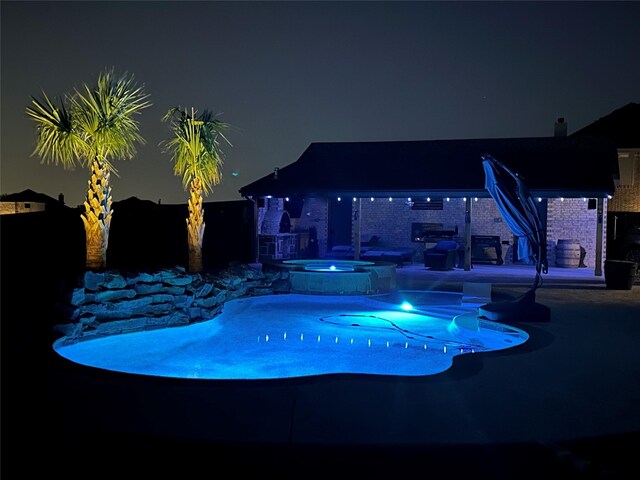 pool at twilight with a pool with connected hot tub and a patio