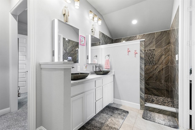 bathroom featuring vanity, vaulted ceiling, a tile shower, and tile patterned flooring