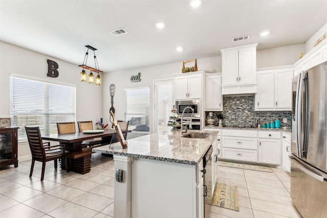 kitchen with pendant lighting, an island with sink, white cabinets, and appliances with stainless steel finishes