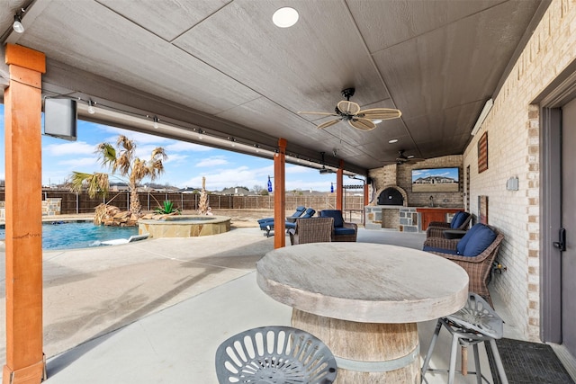 view of patio / terrace with outdoor dry bar, a pool with connected hot tub, a ceiling fan, exterior kitchen, and a fenced backyard