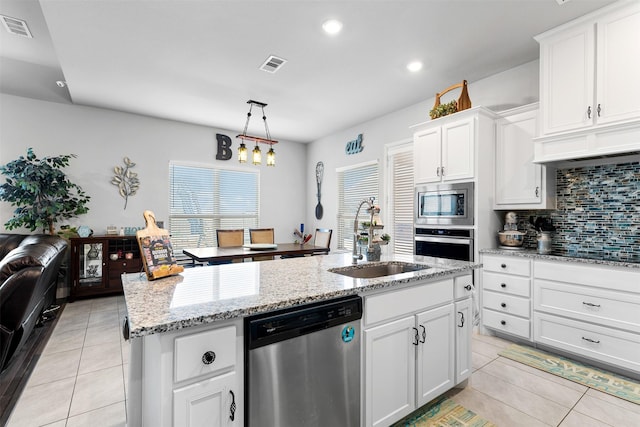 kitchen featuring visible vents, a kitchen island with sink, stainless steel appliances, white cabinetry, and a sink