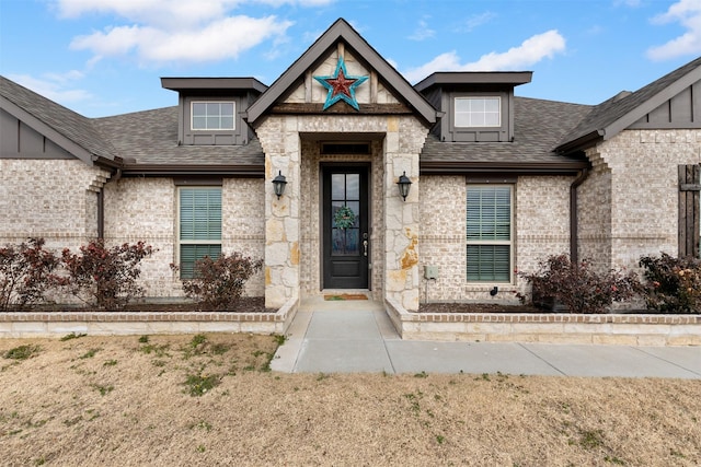 view of front of property featuring brick siding, roof with shingles, and a front lawn